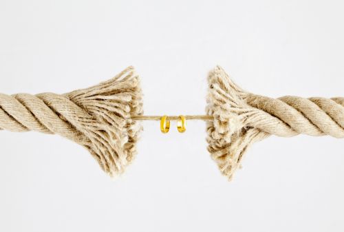 Wedding rings hanging on by a thread of a breaking rope