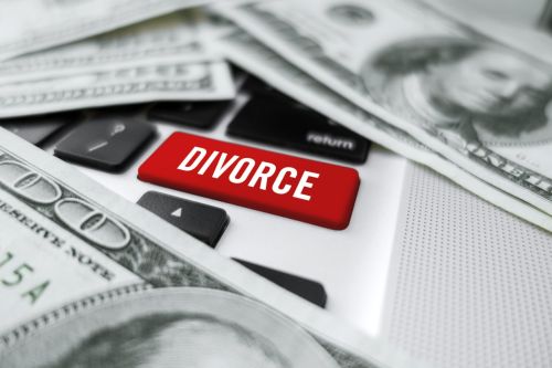 Looking down on a magnifying glass “Divorce” computer button and dollar bills concept for discovery in divorce.