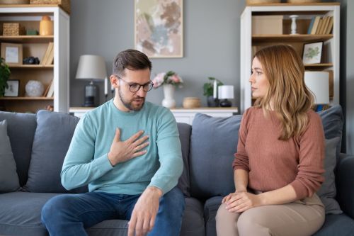 A man and a woman sit on a sofa having a deep discussion. Visual concept for a family law blog discussing tips for navigating divorce communication.