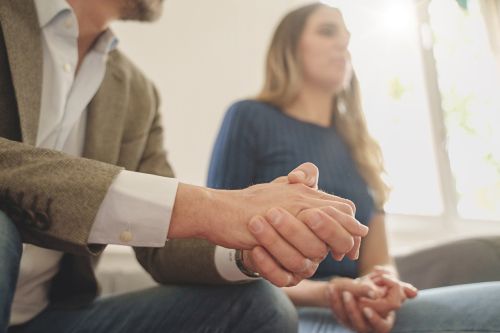 An anxious couple. Close up of the man's hands. Visual concept for a family law blog discussing the key differences between collaborative and traditional divorce.