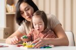 Social emotional development of children with down syndrome, the girl plays in the classroom with educational toys