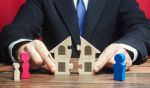Close up of hands pulling apart a puzzle house. Visual concept for legal blog discussing equitable distribution and differences between marital and separate property.