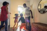 Divorced parents are standing in the hall as their children are running towards an open front door in excitement Visual concept for legal blog discussing 50/50 child custody in Utah.