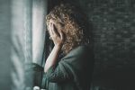 Domestic Violence portrait of woman at home in the dark looking outside the window. Visual concept for legal blog offering steps you can take to protect yourself if domestic violence arises during divorce.