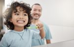 Shot of son and father brushing teeth, visual concept for a Utah family lawyer blog discussing Utah Child Support Guidelines.